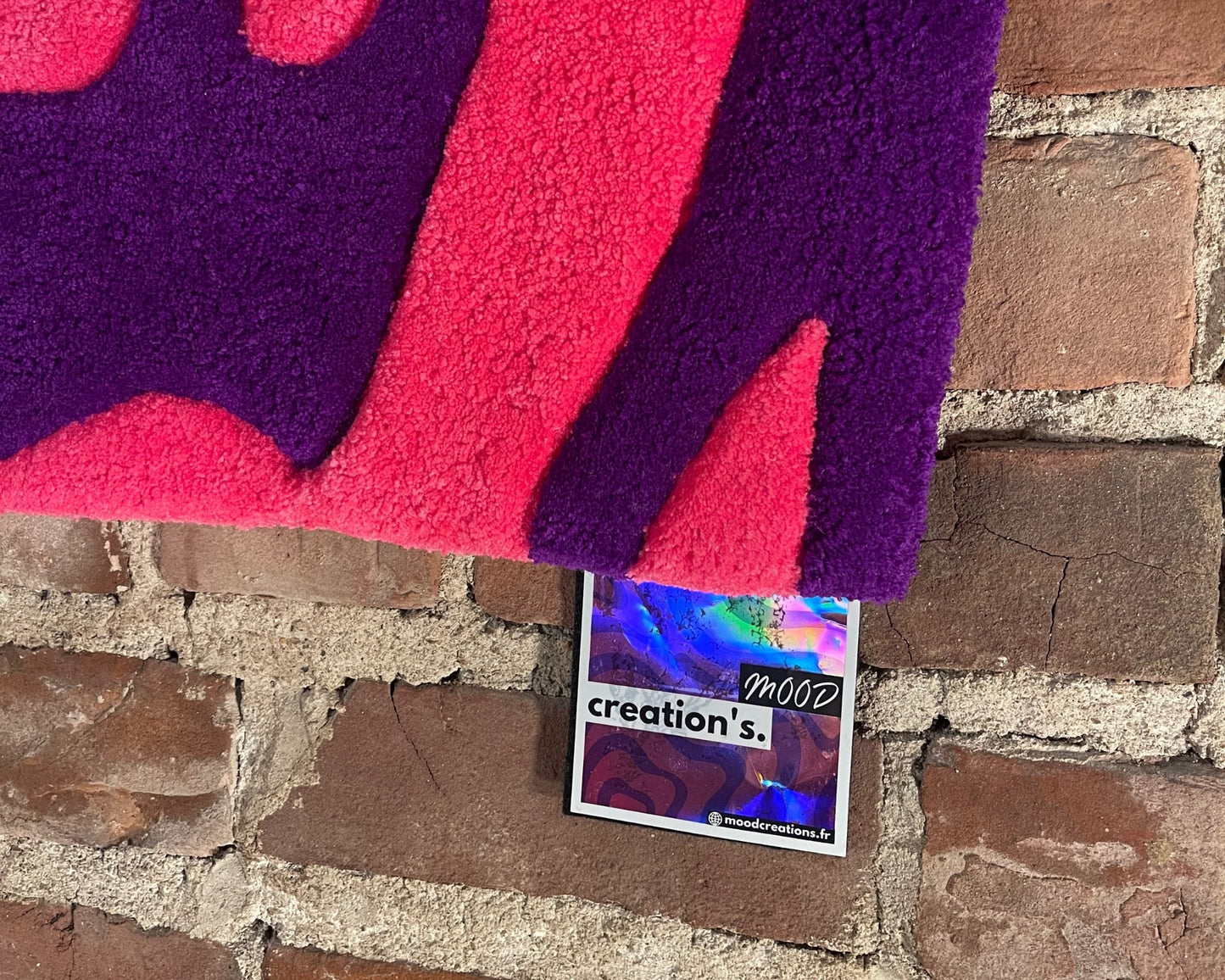 Détail du tapis représentant une silhouette féminine stylisée dans un contraste de rose intense et violet profond.