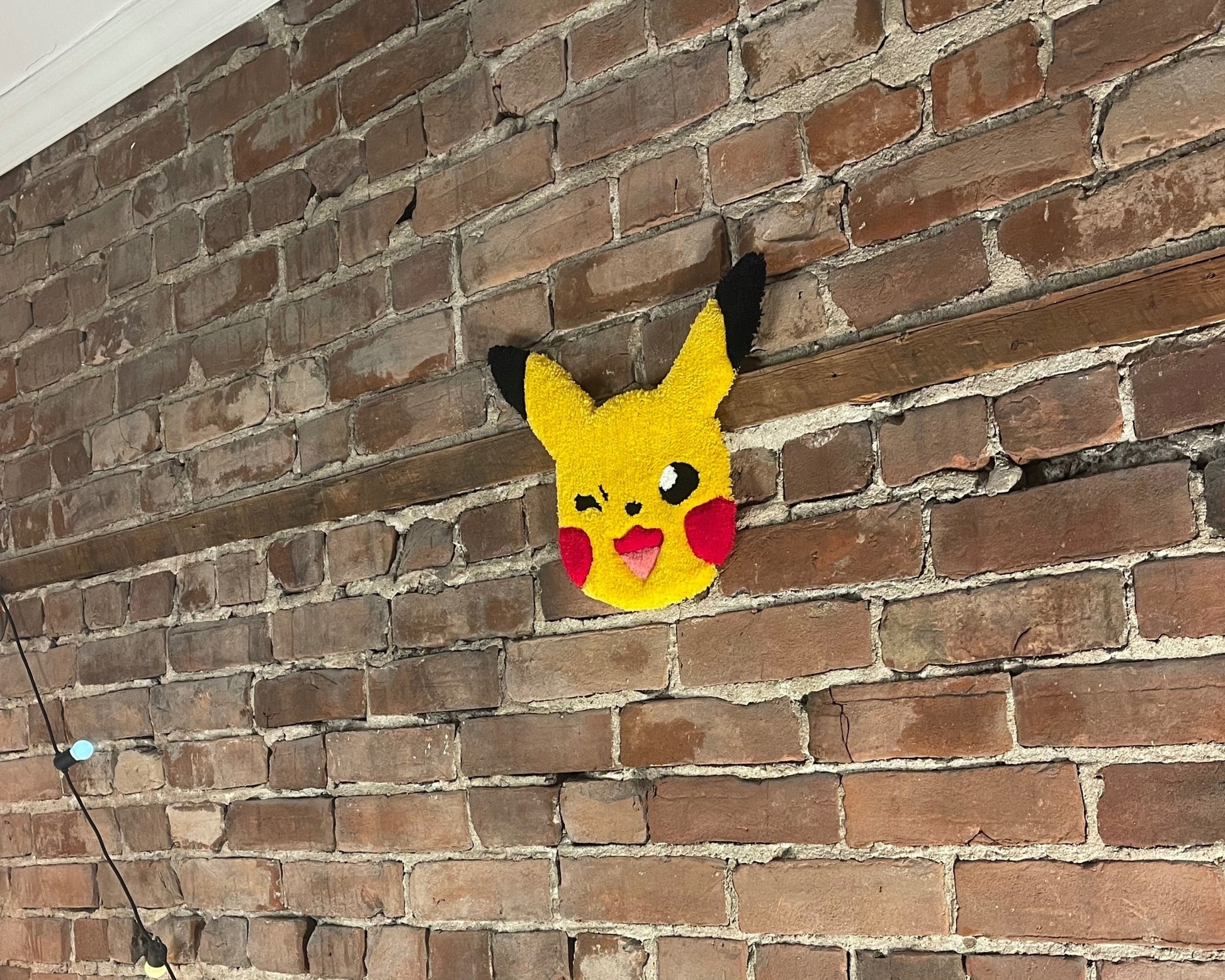 Tapis décoratif qui représente Pikachu accroché au mur