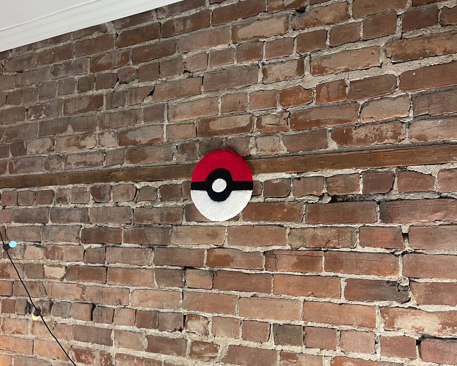 Tapis sur mesure accroché au mur qui représente un pokeball de Pokemon