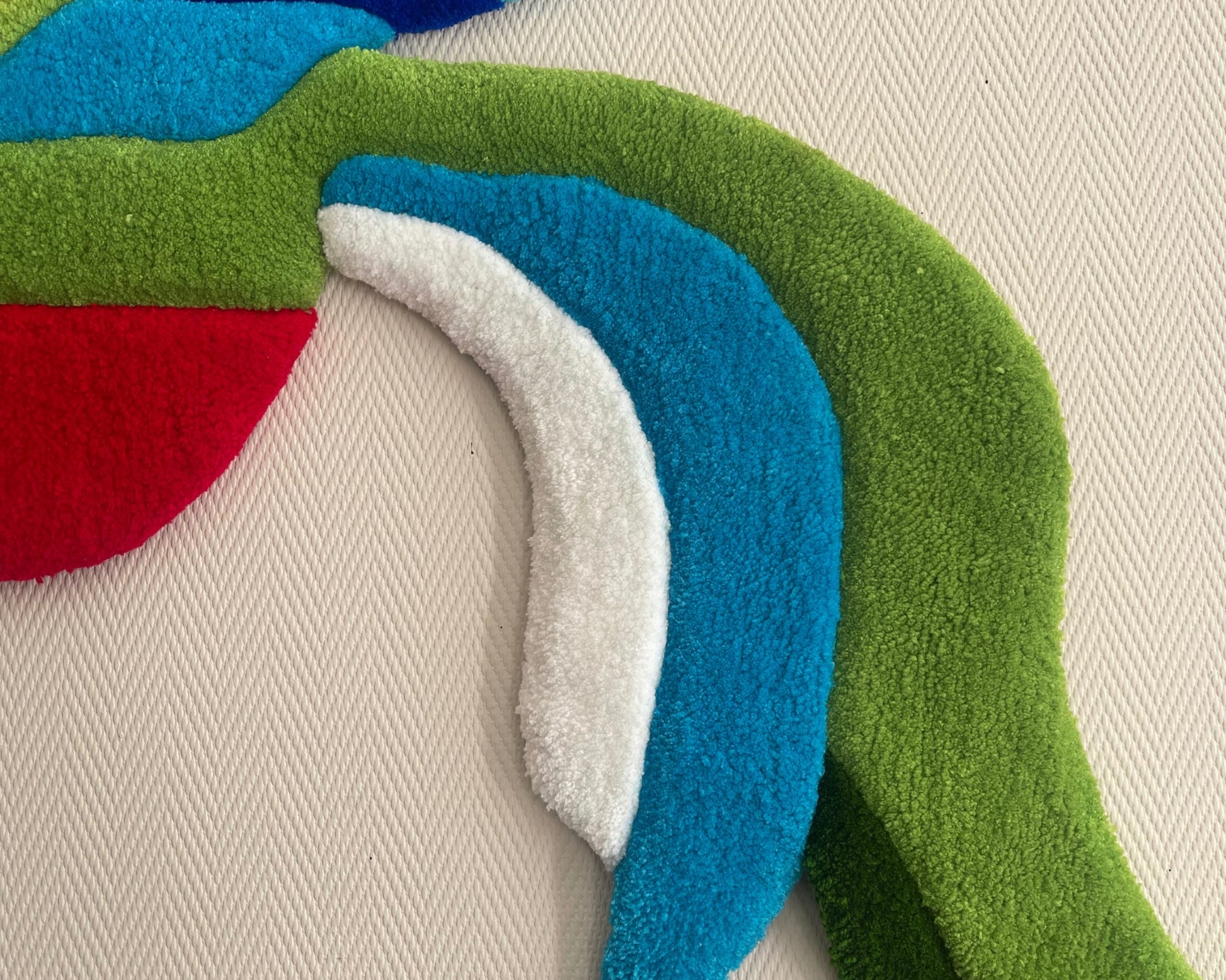 Détail du tufting : relief et texture de la laine acrylique sur le tapis Quetzal.