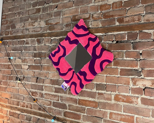Pièce unique tuftée main intégrant un miroir au centre d’un motif ondulé rose-violet.
